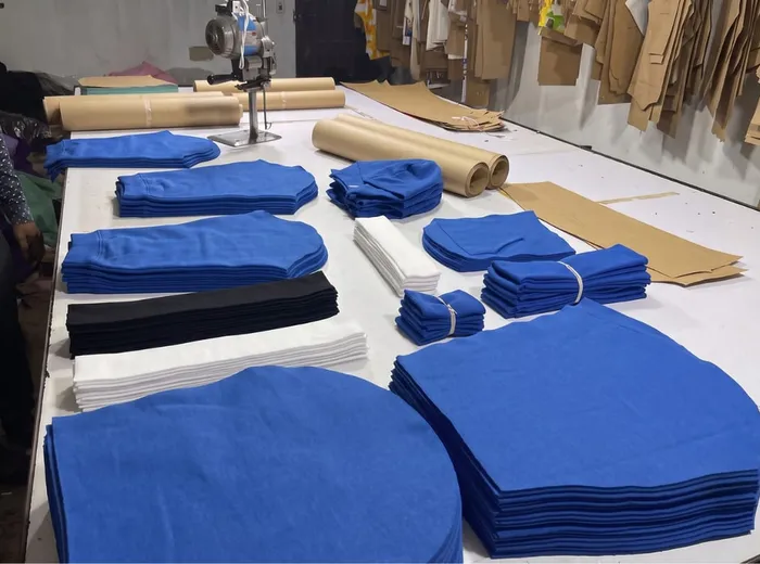 A cutting table with matched blue and white fabric panels staged in stacks, pattern paper still hanging behind.