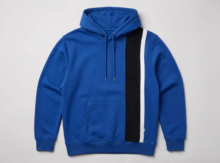 A flat-lay of a blue pullover hoodie with a black-and-white color-blocked side panel and piping.