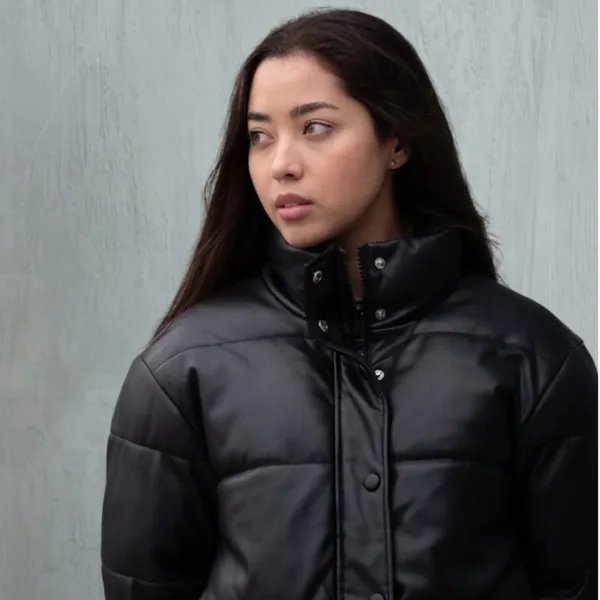 A model wearing a black faux-leather puffer jacket with snap hardware.