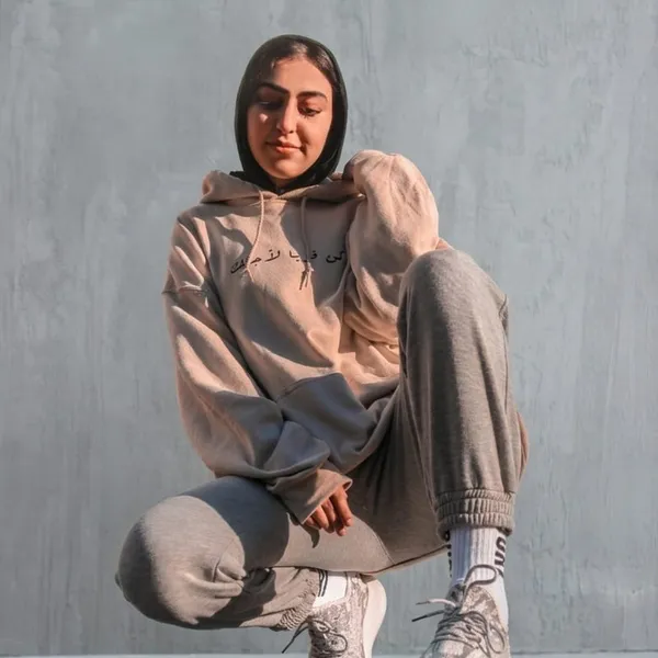A person crouching in a tan and grey screen-printed jogger set.