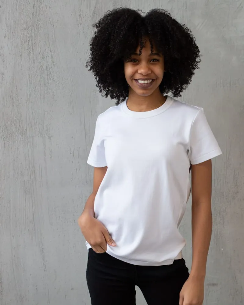 A model in a plain white crew-neck cotton T-shirt against a concrete backdrop.
