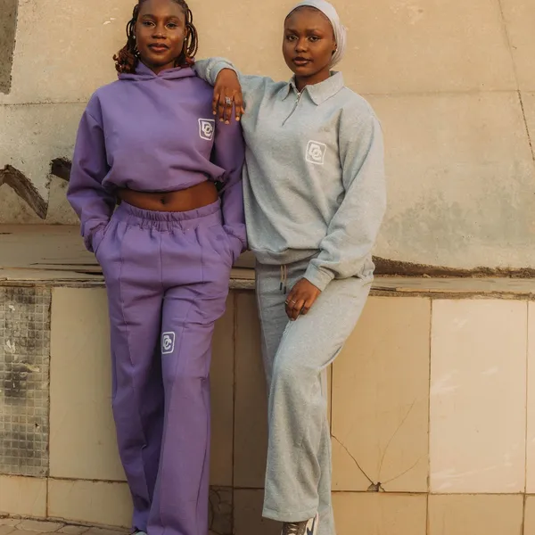 Two people wearing matched lavender and grey tracksuit sets.