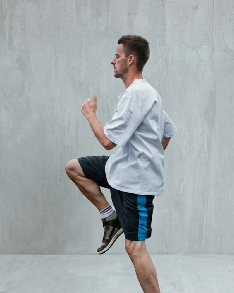 A model mid-stride in an oversized white training tee and dark shorts.