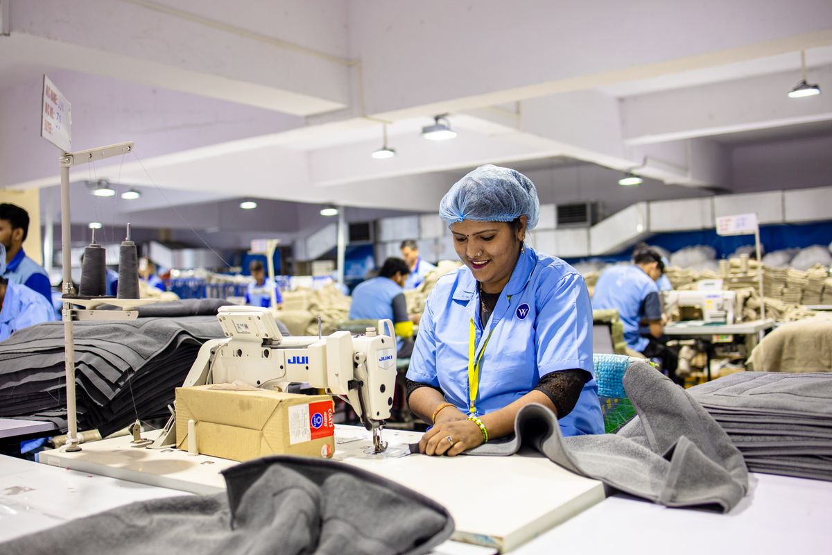 Machinists at industrial sewing machines on a garment production floor.