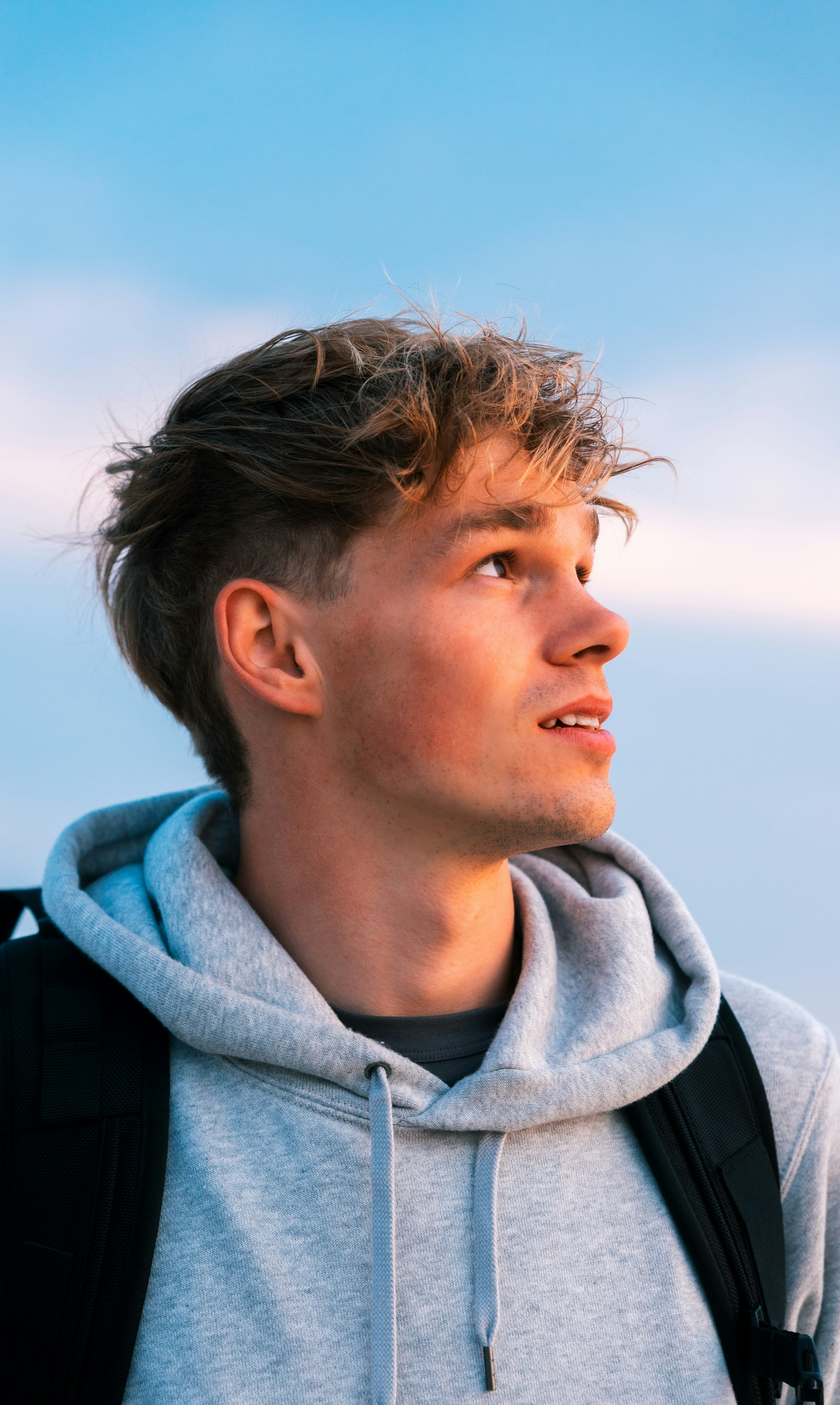 A person wearing a plain heavyweight hoodie outdoors.